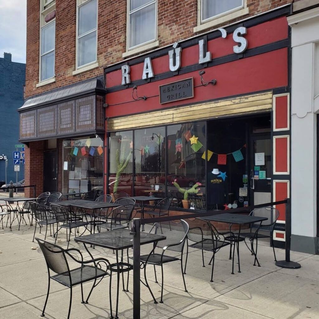 Shot if the Raul's exterior. it is red with silver block letters and black tables and chairs.