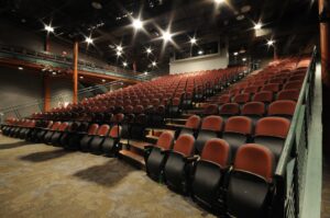 Lights shine on empty red and black theater seats.