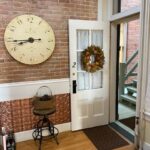 Front door open inside room entrance with brick wall and big clock