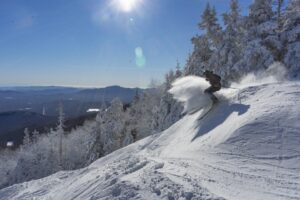 A skier flies down fresh powder on a sunny day.