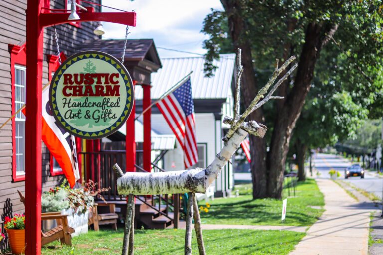 Outside sign of Rustic Charm in Chestertown, NY with deer sculpted out of birch logs