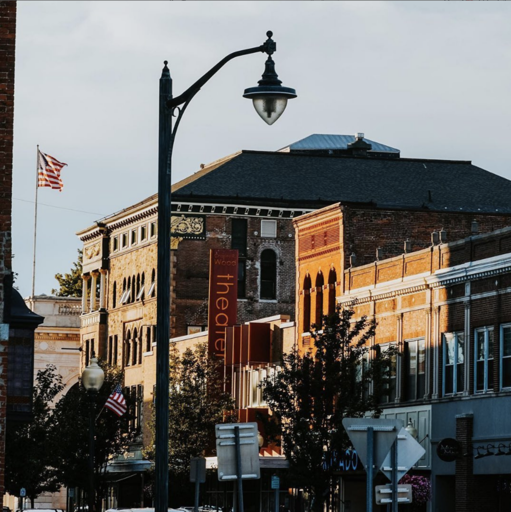 A sunset view of Glen St in Glens Falls. You can see a few rooftops, including the Wood Theater sign.