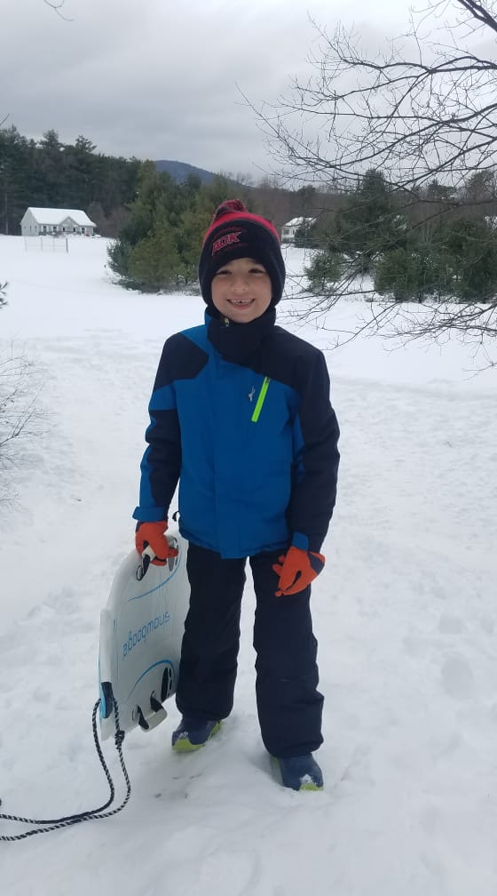Kid standing in the snow smiling at camera