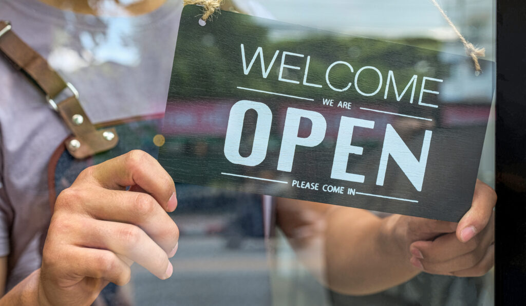 Close up of person holding an open sign