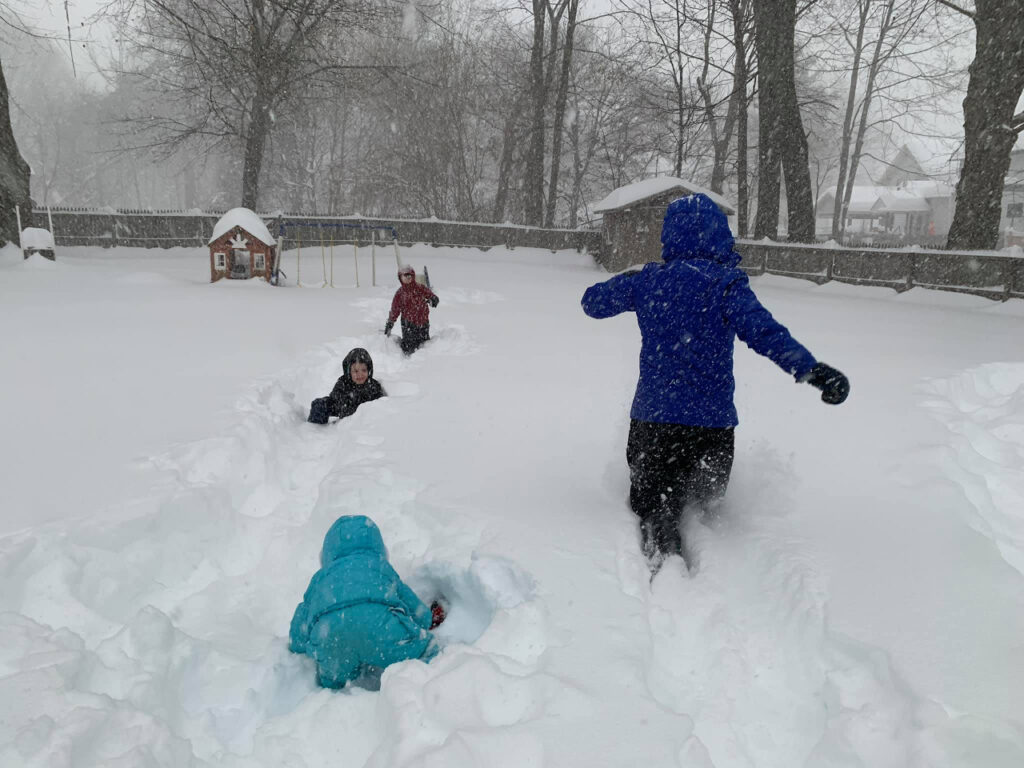 four people playing in the snow