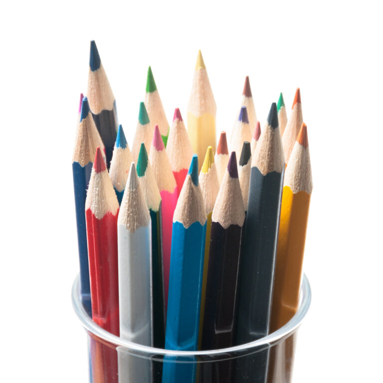 A clear plastic cup holds sharp, multi-colored pencils.