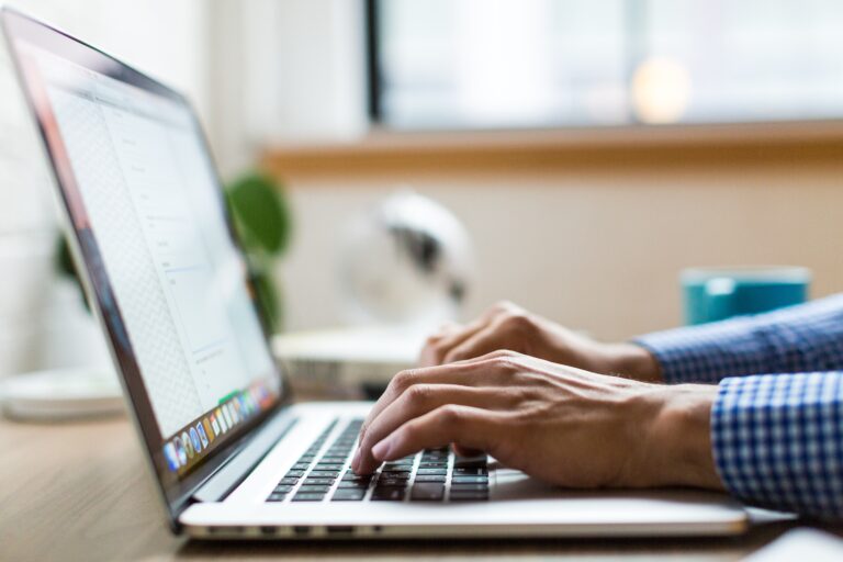 Hands typing on a laptop