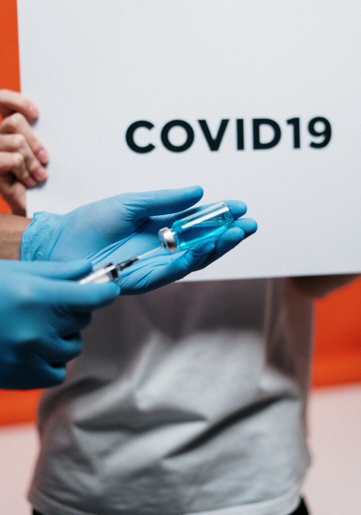 Hands holding a syringe in front of a sign that reads COVID19